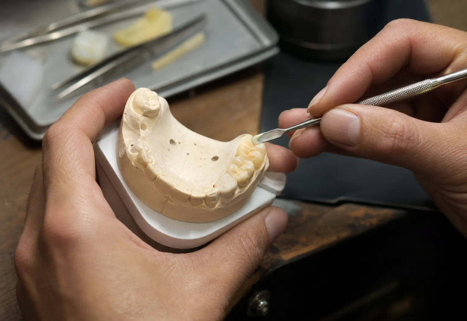 Alçı çene modeli üzerinde spatulayla mum modelaj yapılıyor, laboratuvar tezgâhında